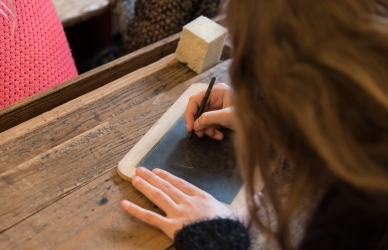Pige skriver med griffel på lille tavle i "Den Gamle Skolestue" 
